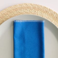 a white plate with a blue napkin on it and a straw hat next to it