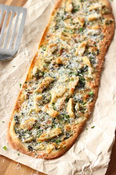 a pizza sitting on top of a piece of wax paper next to a spatula