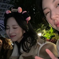 two women with hair clips on their heads posing for the camera