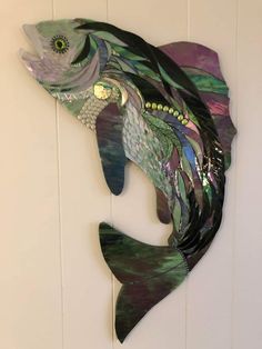 a metal fish sculpture hanging on the side of a wall