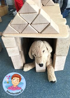 a stuffed dog is hiding under a toy house