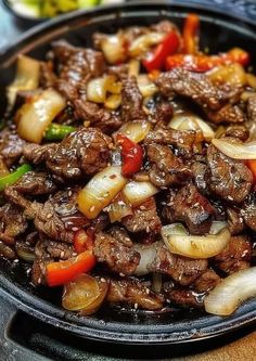 beef and onions stir fry in a skillet on top of a table with other food items