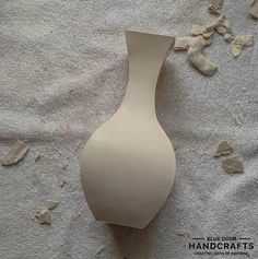 a white vase sitting on top of a bed covered in broken up pieces of paper