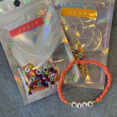 two bags filled with beads and bracelets sitting on top of a blue cloth covered floor