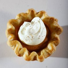 a small pastry with whipped cream in it on a white table top, ready to be eaten