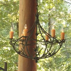 a chandelier hanging from the side of a wooden pole in front of trees