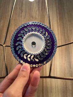 a hand holding a purple and white glass candle holder