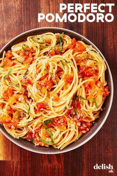 a bowl filled with pasta and sauce on top of a wooden table