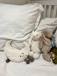 two stuffed animals sit on a bed next to an empty bottle and teddy bear,