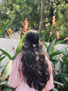 the back of a woman's head with long hair and flowers in the background