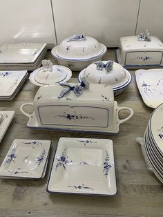 a table topped with lots of white and blue dishes next to each other on top of a wooden floor