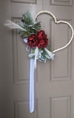 a heart - shaped wreath with flowers and pearls hangs on the front door to welcome guests