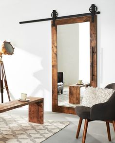 a room with a chair, mirror and table in it