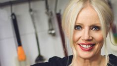 a woman with blonde hair and blue eyes smiles at the camera while standing in a kitchen