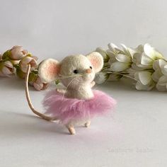 a small mouse in a pink tutu with flowers on the side and behind it