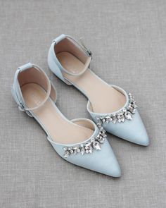 a pair of blue shoes with jeweled details on the toe and heel, sitting on a gray surface