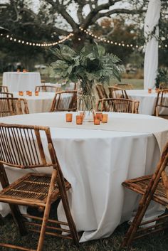 the table is set with white linens and wooden chairs for guests to sit at