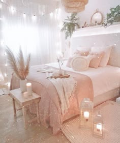 a bed with pillows, blankets and candles on the floor in front of a window