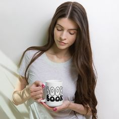 a woman holding a coffee mug with the words look book on it in front of her face