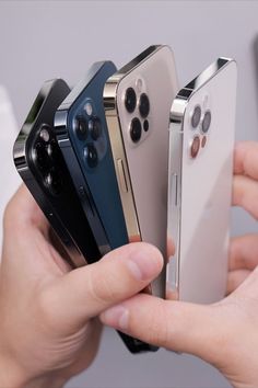 a person holding four different colored phones in their hands