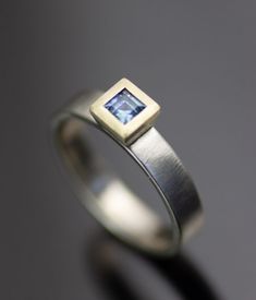 a ring with a square shaped blue topazte in the center, on a gray background