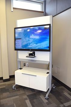 a flat screen tv mounted to the side of a wall next to a white cabinet