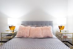 a bed with two lamps on either side and a fur pillow on the headboard