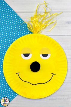 a paper plate with a yellow face on it and a blue polka doted background