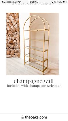 a gold metal shelf sitting on top of a wooden floor next to a stone wall