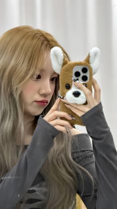 a woman holding up a stuffed animal in front of her face with long blonde hair