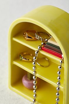 a yellow shelf with rings and jewelry on it