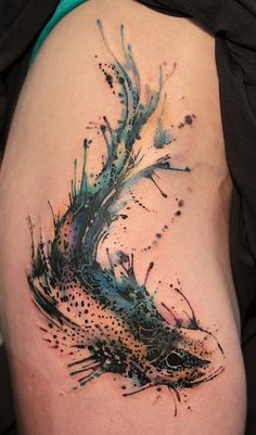 a fish tattoo on the back of a woman's thigh, with watercolor splashes all over it