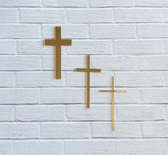 two gold crosses on a white brick wall