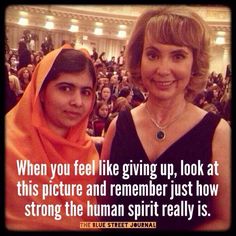 two women standing next to each other in front of a crowd with a quote on it