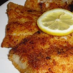 fish fillets with lemon wedges on a white plate