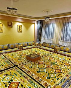 a living room filled with yellow couches and rugs on the floor next to windows