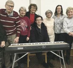 a group of people standing next to each other in front of a keyboard