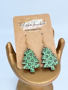 a pair of green earrings on top of a wooden stand in front of a card