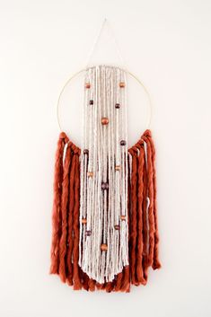 an orange and white dream catcher hanging on a wall next to a potted plant