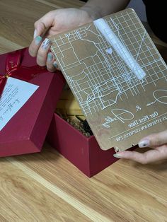 two hands are opening a box with a map on it and the lid is open