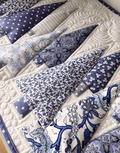 a blue and white quilted bed topped with lots of pillows