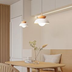 a wooden table sitting under two lights next to a white chair and vase with flowers on it