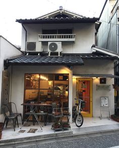 the outside of a small restaurant with tables and chairs in front of it's door