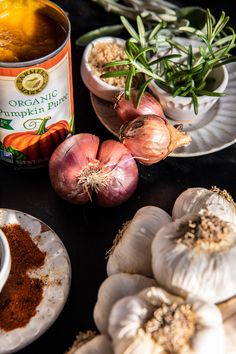 an assortment of spices and seasonings on a black counter top with garlic, cloves, and other ingredients