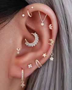 a woman wearing ear piercings with stars and moon designs on the side of her ear