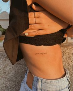 a woman's stomach with the word love tattooed on it