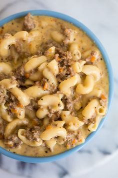 a blue bowl filled with macaroni and cheese on top of a white table