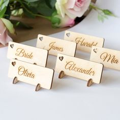 wooden name tags with hearts on them sitting next to pink roses and flowers in the background