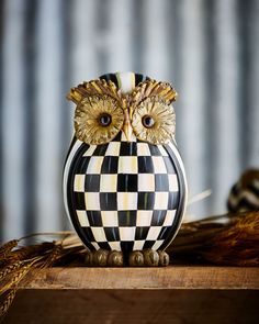 an owl figurine sitting on top of a wooden table next to dried grass