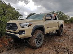 a man driving a tan toyota truck on a dirt road